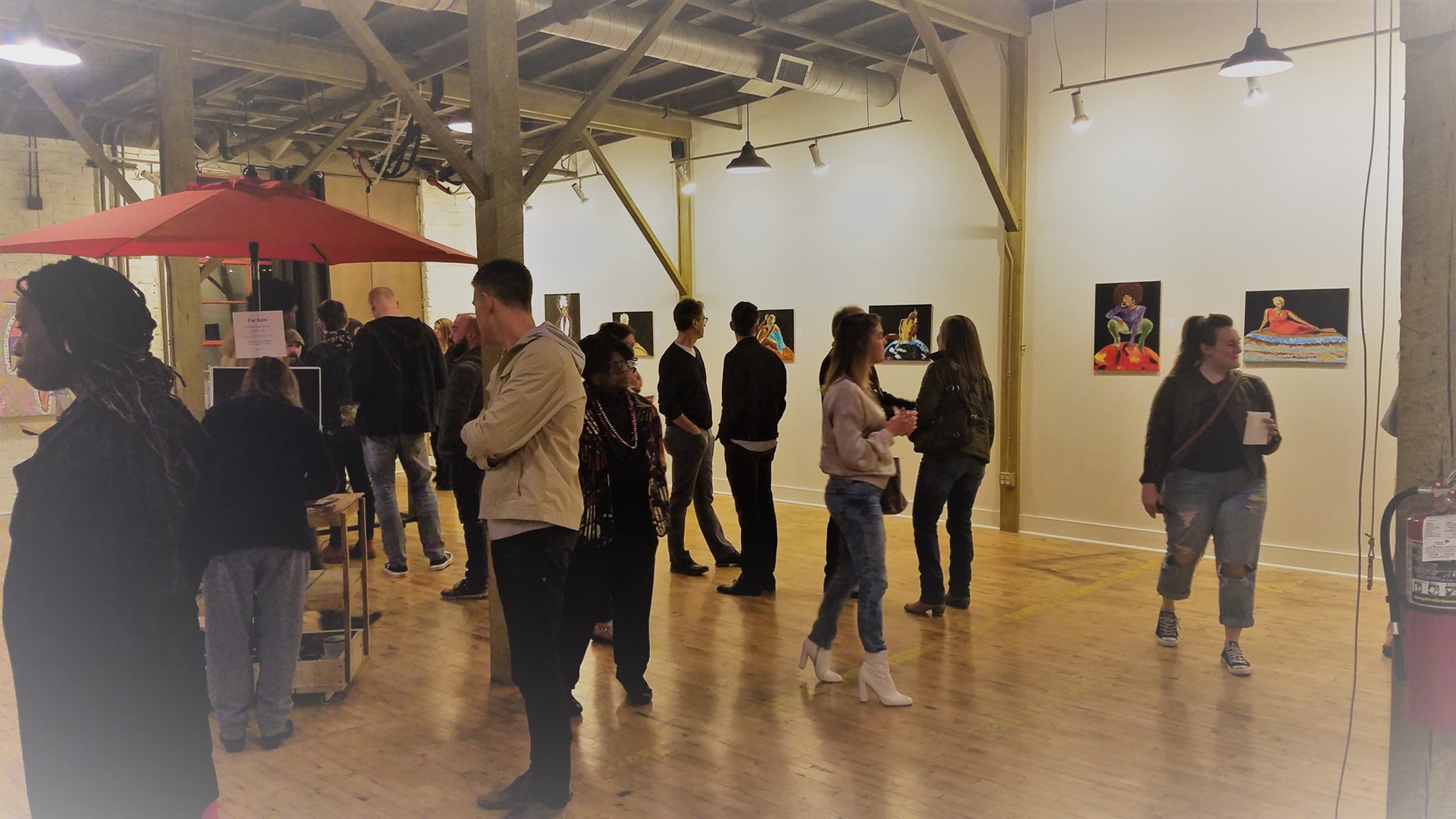 Photo of the opening of the Core Essence by Amanda Downs in abrasiveMedia in February of 2019. A group of people are viewing art on the walls and socializing.